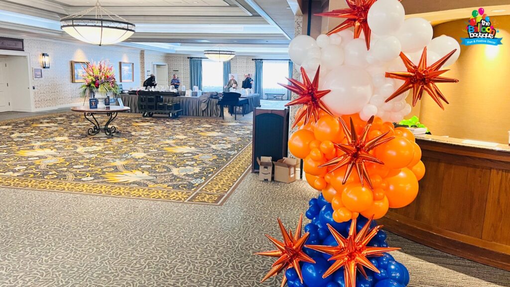 Organic balloon garland in orange and blue, installed at a conference center entrance.