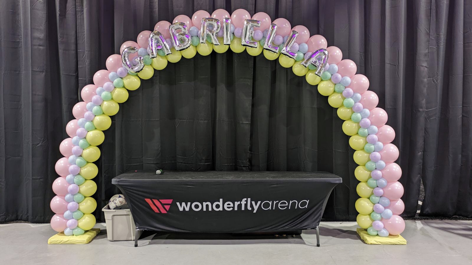 Pastel balloon arch with personalized name for Gabriella's Bat Mitzvah, featuring soft pink, yellow, and blue colors.