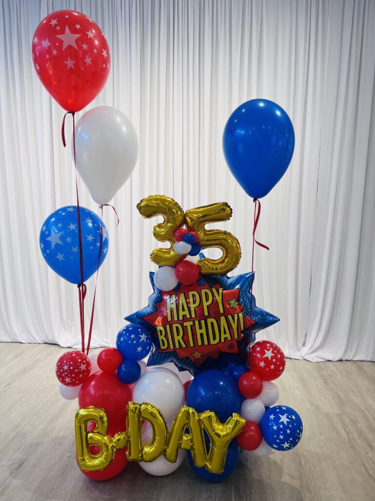 Mixed latex and foil birthday floor bouquet with gold number balloons and birthday message balloons.